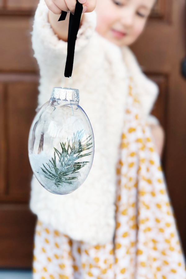 Looking for a quick and easy DIY Christmas ornament to make with your kids? This snow globe ornament is simple, cute, cheap and fun! Perfect for gifting to teachers, neighbors, or grandparents. Make holiday memories with your little one while making these adorable ornaments!