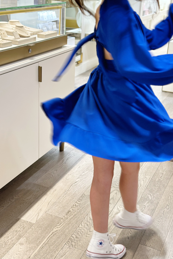 The photo features an eleven year old girl in a bright blue dress twirling in a Kendra Scott jewelry store.