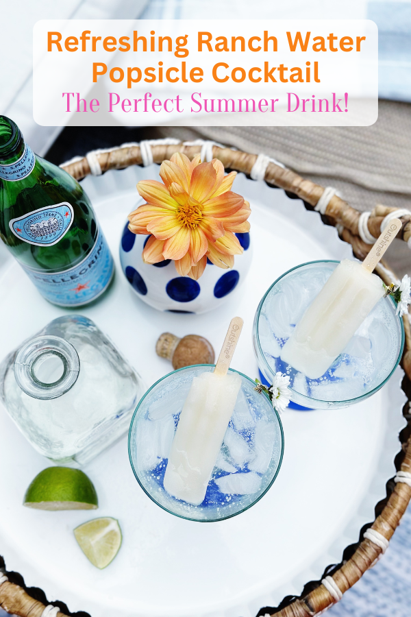 A stylish backyard summer scene featuring a popsicle aesthetic with margarita glasses filled with ice, lime popsicles, and fizzy sparkling water. The woven tray, colorful floral accents, and bright pink sandals create the perfect setting for a popsicle party to enjoy a refreshing ranch water popsicle cocktail.