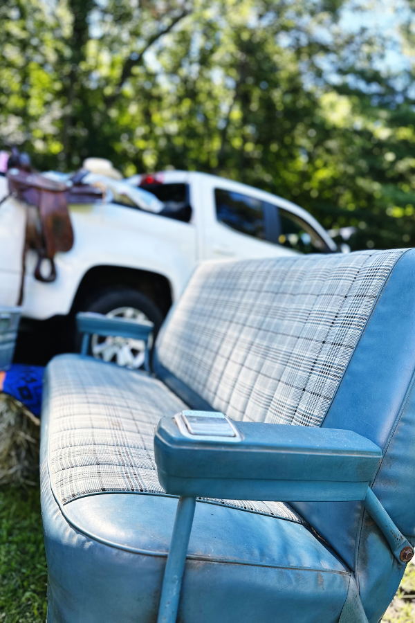 Western bridal shower setting featuring a vintage truck bench seat used as both a photo opportunity and additional seating for guests. In the background, a rustic bar truck serves as the drink station. This cozy and charming setup is perfect for rustic bridal shower ideas decorations or cowgirl wedding celebrations. The vintage truck bench seat adds to the country charm, making it an ideal spot for guests to relax and take photos at a cowgirl hens party or cowboy theme party.