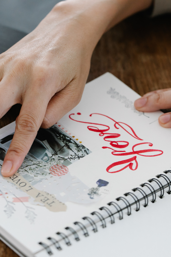 For a unique bridal shower idea this wedding shower guest is creating a scrapbook for the bride-to-be. The book is a small spiral notebook with the word "Love" beautifully hand written at the bottom of the page.