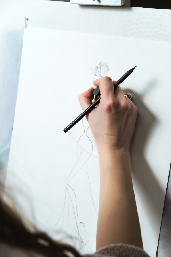 This hostess got a head start on her bridal shower planning by hiring a sketch artist to draw a picture of the bride in her wedding gown. The photo is of an artist holding a pencil and eraser while outlining her wedding dress creation. 