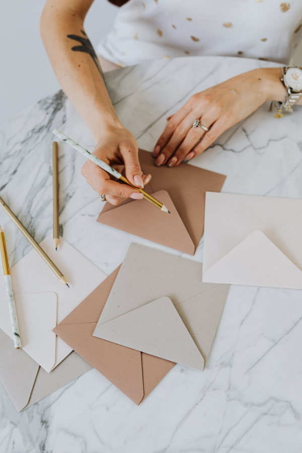 Instead of forcing guests to play unique bridal shower games this wedding shower host is sitting at a table labeling envelopes for her guests to write the bride a sentimental letter.