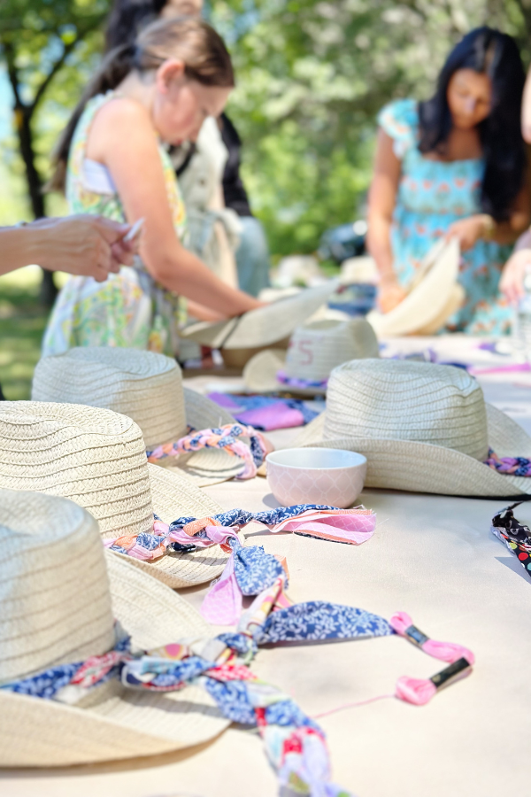 Guests customizing their own cowgirl hats at a DIY hat bar. This fun, interactive activity allows guests to create personalized hats as party favors, making it a memorable experience for a western bridal shower or cowgirl bachelorette party. 