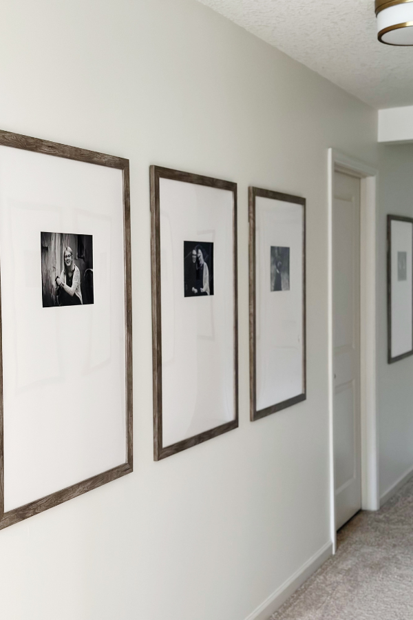 A beautifully styled narrow hallway decorating idea with large framed photos in a symmetrical gallery wall, perfect for modern hallway decor inspiration.