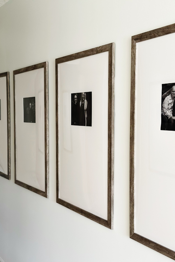 A sophisticated hallway with big picture frame ideas—wooden rustic frames with white mats showcasing classic black-and-white family portraits.