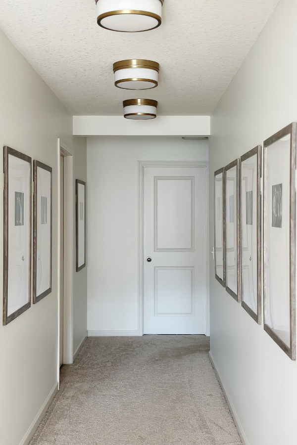 Bright and airy hallway interior design with large framed photos in big frames on wall, creating a timeless and sophisticated home decor style.